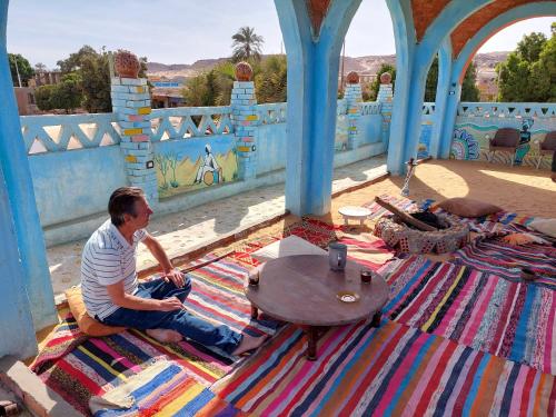 a man sitting on a rug on a floor with a table at Mostafa guesthouse in Najâ€˜ al MadÄbb