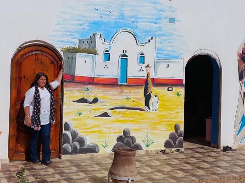 a woman standing in front of a wall with a painting at Mostafa guesthouse in Najâ€˜ al MadÄbb