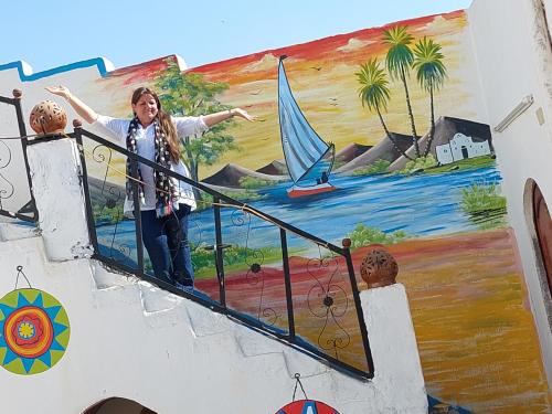 a woman standing on a staircase in front of a mural at Mostafa guesthouse in Najâ€˜ al MadÄbb