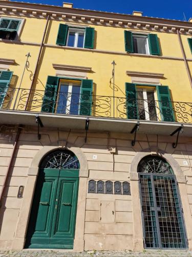 a yellow building with green doors and windows at Piazza Duomo in Tuscania