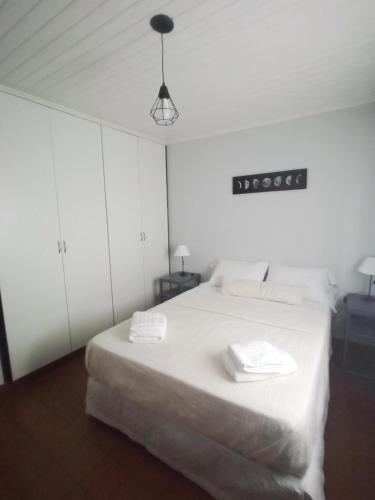 um quarto com uma cama branca com duas toalhas em La casita em Porto Iguaçu