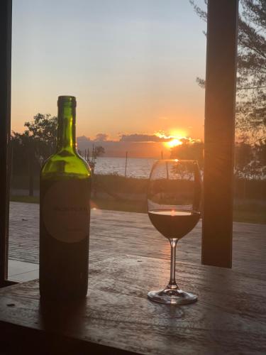 a glass of wine sitting next to a bottle of wine at Lagoon Suites e Gastronomia in Laguna
