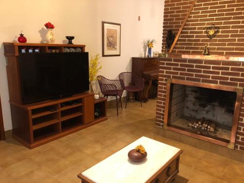 ein Wohnzimmer mit einem Kamin und einem TV in der Unterkunft Recanto Arlecchino in Águas de Lindóia