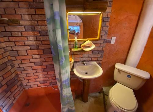 a bathroom with a sink and a toilet and a mirror at YES PAPA! Rooms at 100m from the beach! in Las Galeras