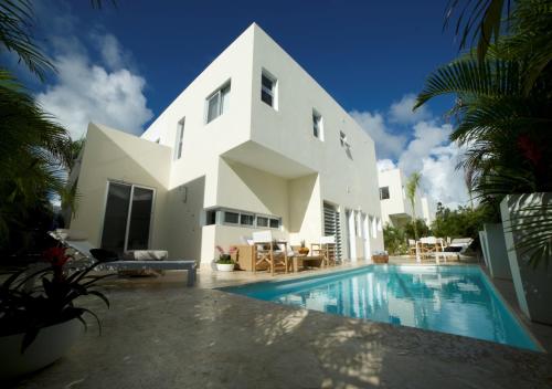 a white house with a swimming pool in front of it at Stylish Luxury San Juan Lakes Villa in Gated Community in Downtown Punta Cana With Private Pool in Punta Cana