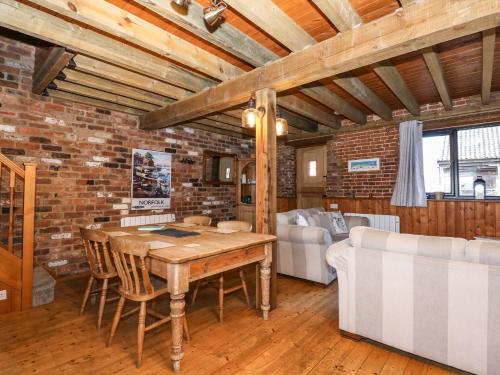 a dining room with a wooden table and a brick wall at The Dairy Barn in Fakenham