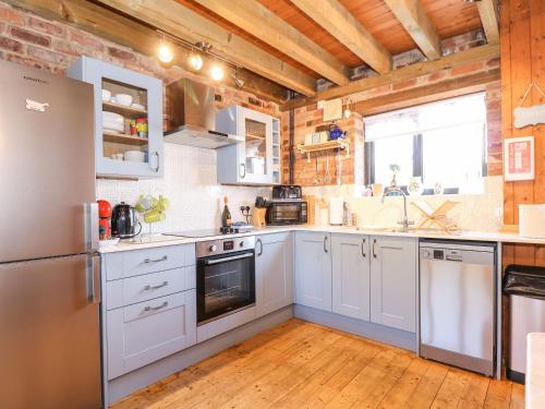 a kitchen with white appliances and a wooden ceiling at The Dairy Barn in Fakenham