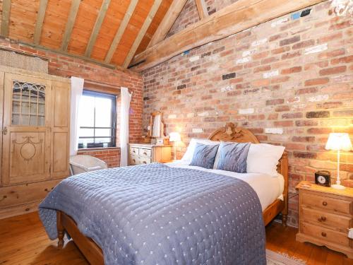 um quarto com uma parede de tijolos e uma cama em The Dairy Barn em Fakenham