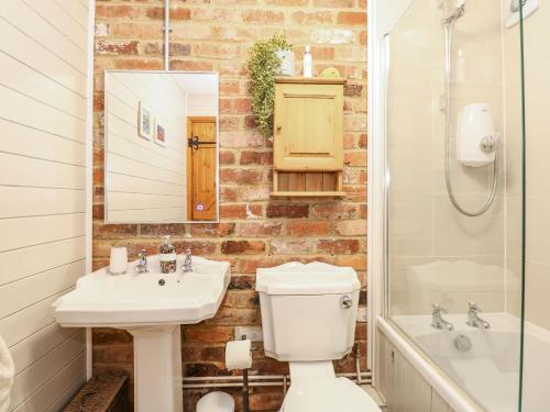 a bathroom with a sink and a toilet and a mirror at The Dairy Barn in Fakenham