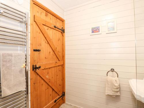 La salle de bains est pourvue d'une porte en bois et d'un lavabo. dans l'établissement The Dairy Barn, à Fakenham