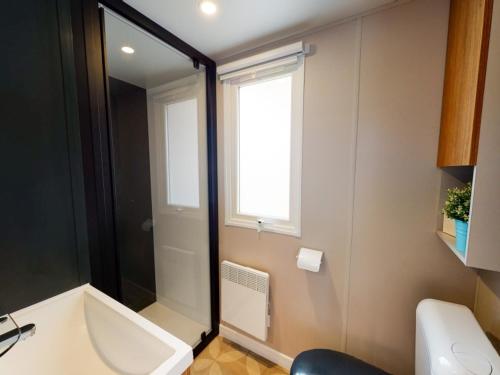 a bathroom with a bath tub and a window at Mobilhome NEUF Mar estang Accès Plage in Canet-en-Roussillon