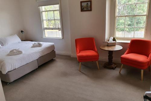 - une chambre avec deux chaises rouges, un lit et une table dans l'établissement Bothwell Hotel of the Highlands, à Bothwell
