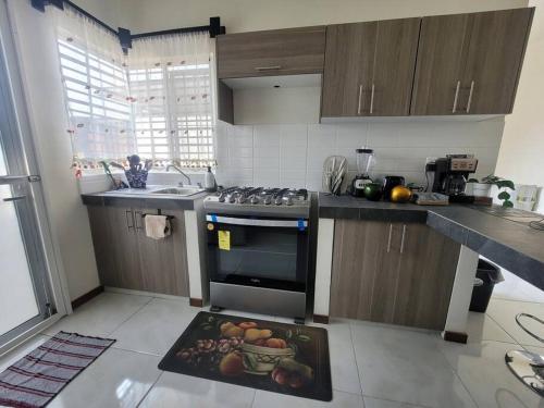 a kitchen with a stove and a bowl of fruit on a rug at Casa totalmente nueva,2 cuartos 2 baños -Muy Segura in Colima