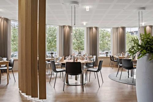uma sala de jantar com mesas, cadeiras e janelas em Hotel Svendborg em Svendborg