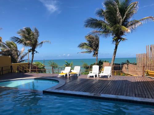 a pool with chairs and palm trees and the ocean at Atlântico Flat -207- Vista ao Mar e Pé na Areia in Natal
