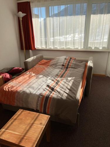 a bed in a room with a table and a window at Haus Atlantic Leukerbad in Leukerbad