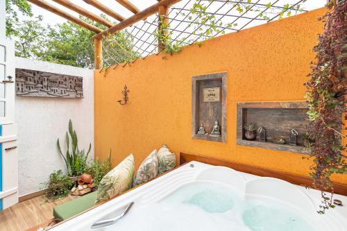 a hot tub in a patio with an orange wall at CasinhaPiri in Pirenópolis