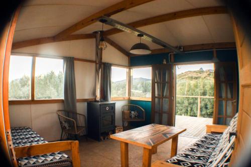 Habitación con mesa, sillas y ventanas. en Cuatro Vientos Patagonia - Lago Huechulafquen en Junín de los Andes