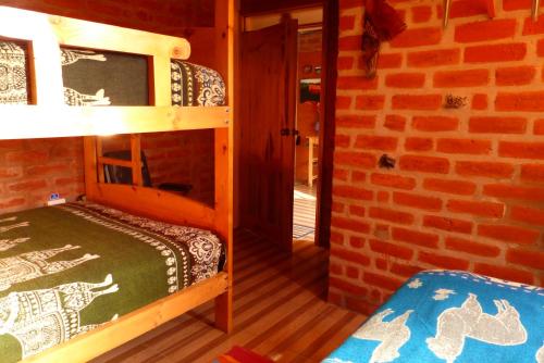 a room with two bunk beds and a brick wall at Hostal La Casa Amarilla City in Baños