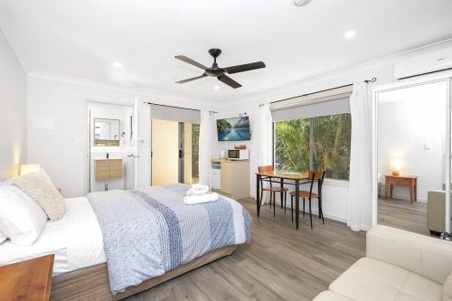 a white bedroom with a bed and a living room at Tiarri Terrigal in Terrigal