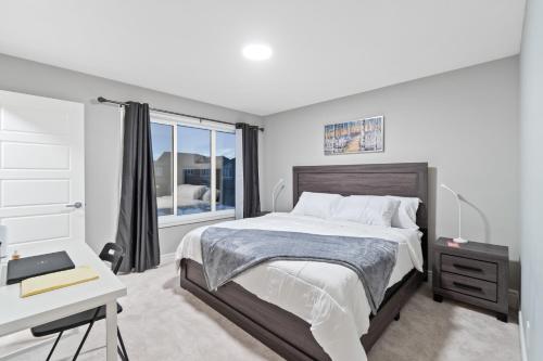 Schlafzimmer mit einem Bett, einem Schreibtisch und einem Fenster in der Unterkunft Upscale Urban Oasis- Stylish Townhome Getaway-Comfort for Family, Work and Longer Visits in Edmonton