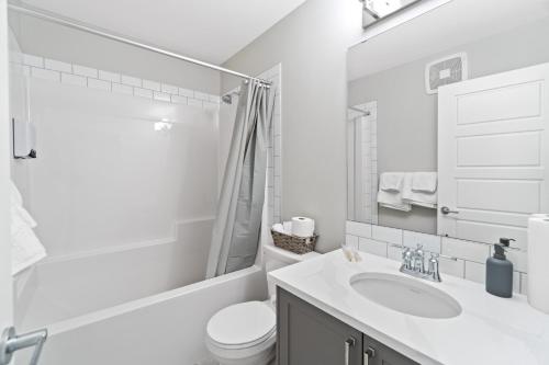 Baño blanco con lavabo y aseo en Upscale Urban Oasis- Stylish Townhome Getaway-Comfort for Family, Work and Longer Visits en Edmonton