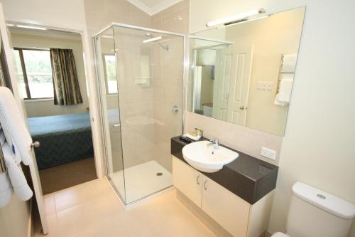 a bathroom with a sink and a glass shower at Brisbane Gateway Resort in Rochedale