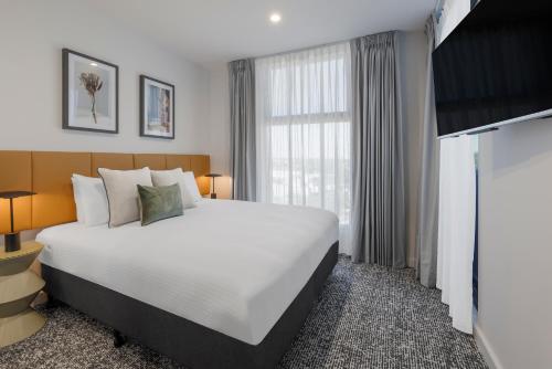 a bedroom with a large bed and a large window at Punthill Essendon North in Melbourne