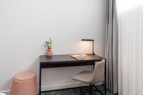 a desk with a lamp and a chair in a room at Punthill Essendon North in Melbourne