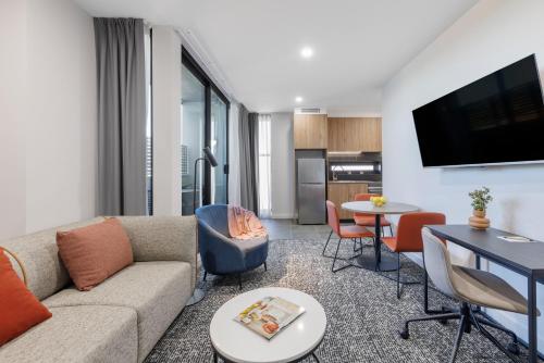 a living room with a couch and a table with chairs at Punthill Essendon North in Melbourne