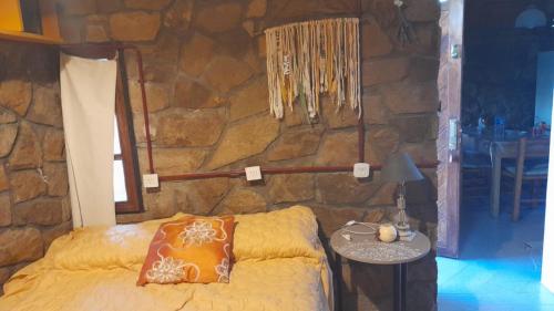 a bedroom with a bed and a stone wall at Filippo in Zapala