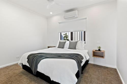 a white bedroom with a large bed and a window at Port Lincoln Beachfront Apartments in Port Lincoln