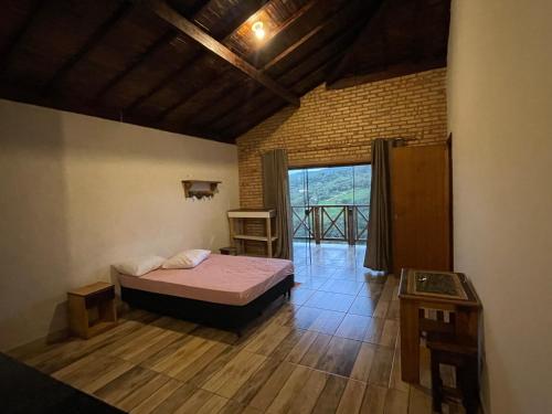 een slaapkamer met een bed en een houten vloer bij Casa 4 Estações in Lima Duarte