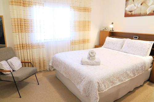1 dormitorio con 1 cama, 1 silla y 1 ventana en Capon Cottage, en Broken Hill