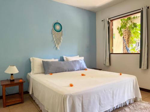 a bedroom with a large white bed with orange flowers on it at Chez Max Pousada in Morro de São Paulo