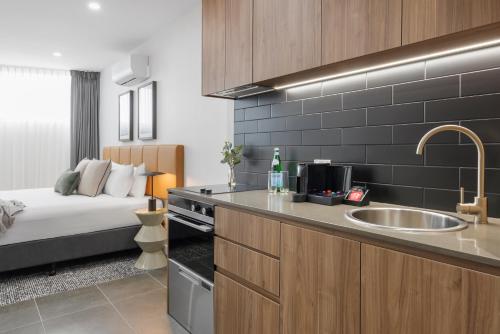 a kitchen with a sink and a bed in a room at Punthill Essendon North in Melbourne