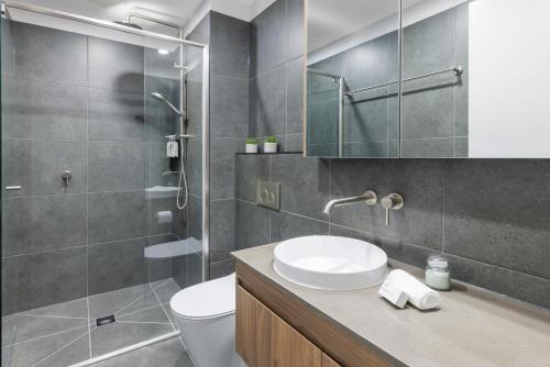 a bathroom with a toilet and a sink and a shower at Punthill Essendon North in Melbourne