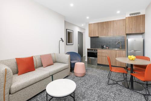 a living room with a couch and a table at Punthill Essendon North in Melbourne