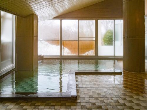 einen Pool mit Wasser in einem Zimmer mit Fenstern in der Unterkunft 津川温泉 清川高原保養センター in Aga