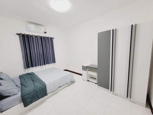 a small bedroom with a bed and a refrigerator at Mara's holiday house in Pattaya South