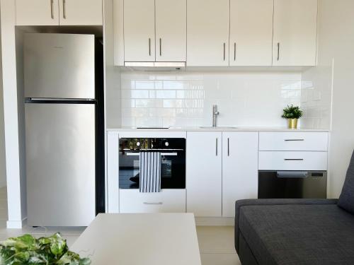 a kitchen with white cabinets and a black refrigerator at One on Harris Apartments in Wellington Point