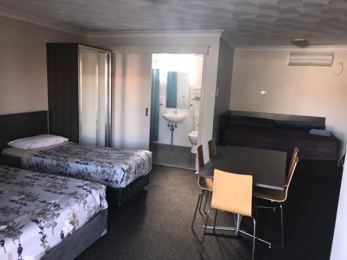 a hotel room with two beds and a table and chairs at Narellan Motor Inn in Narellan