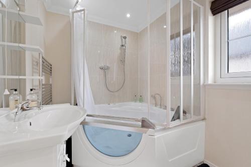 Baño blanco con bañera y lavamanos en Taigh d'Luxe, en Inverness