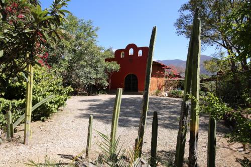 a garden with a red building in the background at Huayápam Yù'ú Lodge in San Andrés Huayapan