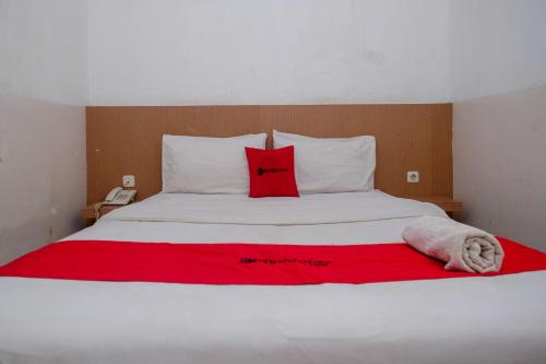 a large white bed with red pillows on it at RedDoorz at Pengayoman Panakkukang 2 Makassar in Makassar