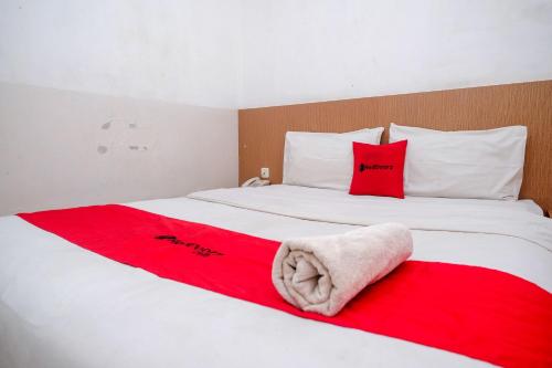 a white bed with red pillows and a red blanket at RedDoorz at Pengayoman Panakkukang 2 Makassar in Makassar