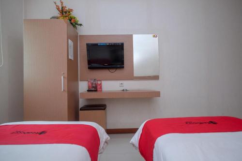 a hotel room with two beds and a tv at RedDoorz at Pengayoman Panakkukang 2 Makassar in Makassar