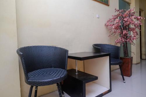 zwei Stühle neben einem Tisch und einer Pflanze in der Unterkunft RedDoorz @ Pengayoman Panakkukang 2 in Makassar