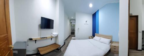 a bedroom with a white bed and a television at 稻薌食旅民宿Daoxiang Travel in Fuli