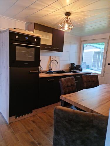 a kitchen with black appliances and a wooden table at Ferienhaus Lucie Kiebitzsee in Falkenberg